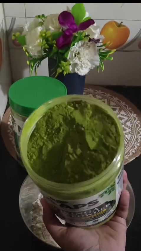 An open jar of bright green NAAPS moringa powder